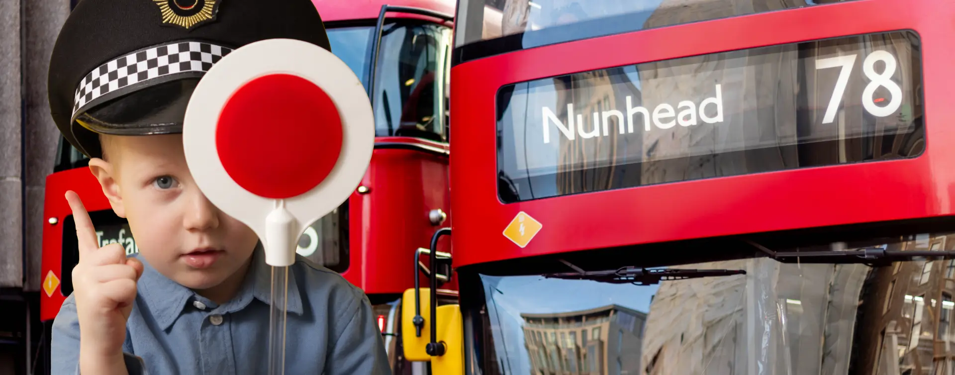 Kind in britischer Polizeiuniform hält ein rotes Stoppschild neben einer roten Telefonzelle