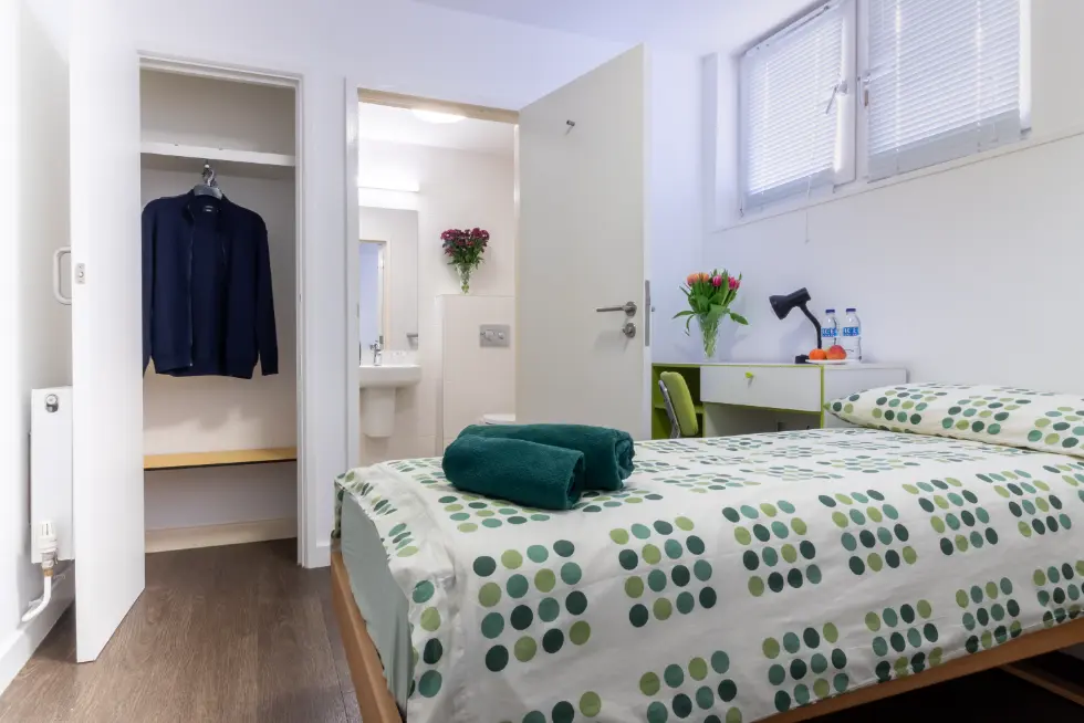 Blick ins Ensuite-Essential-Zimmer mit Bett, Kleiderschrank und Bad